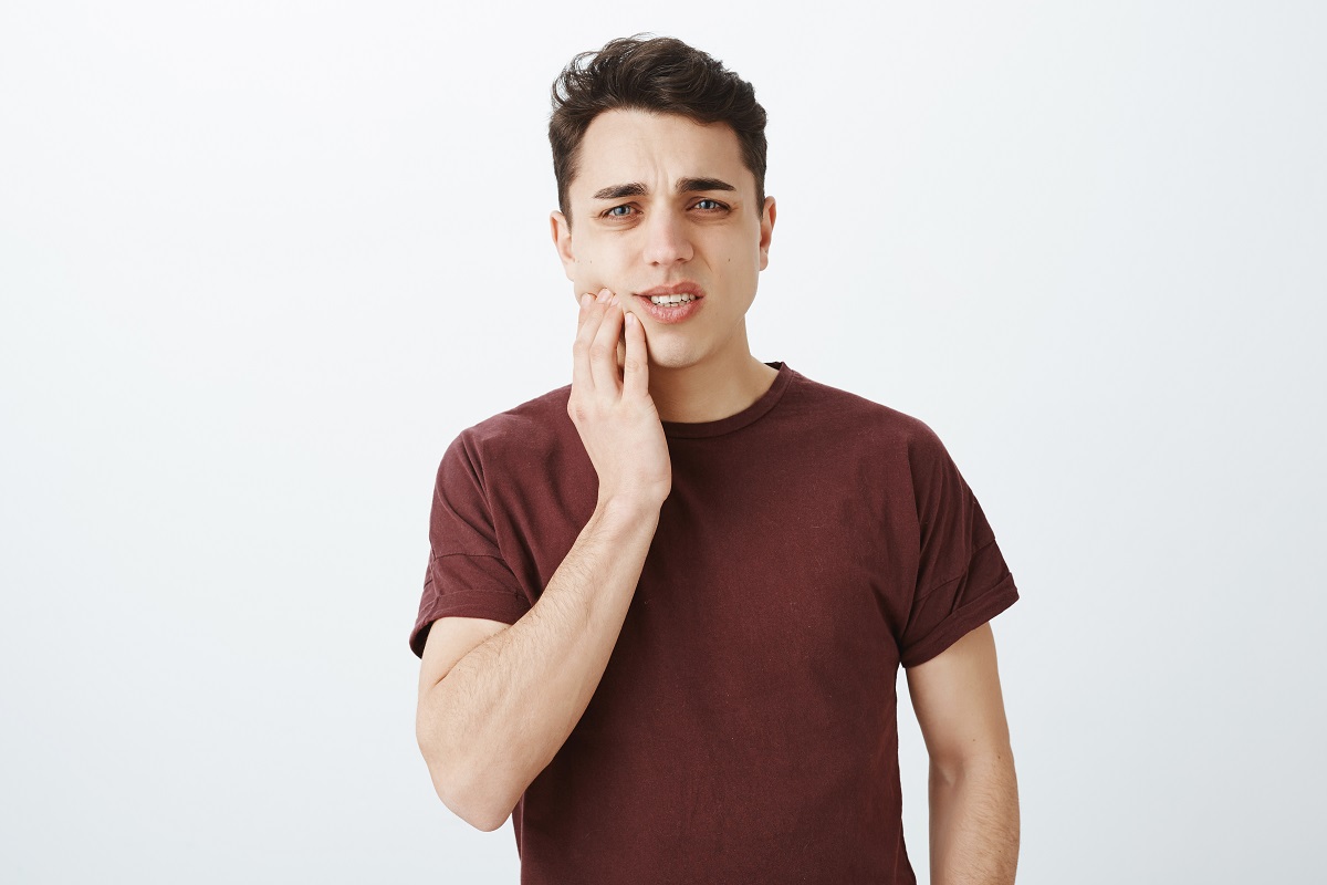 man touching his jaw, showing signs of dental discomfort